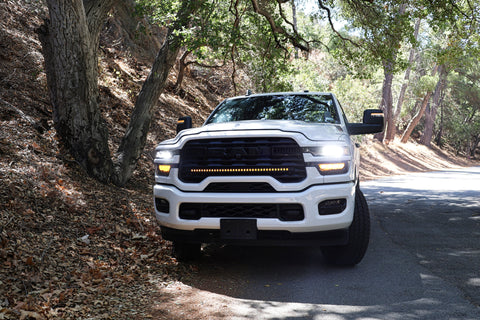 2025+ RAM 2500 light bar 40in slim curved LED installed on white RAM 2500 truck front grille on forest road