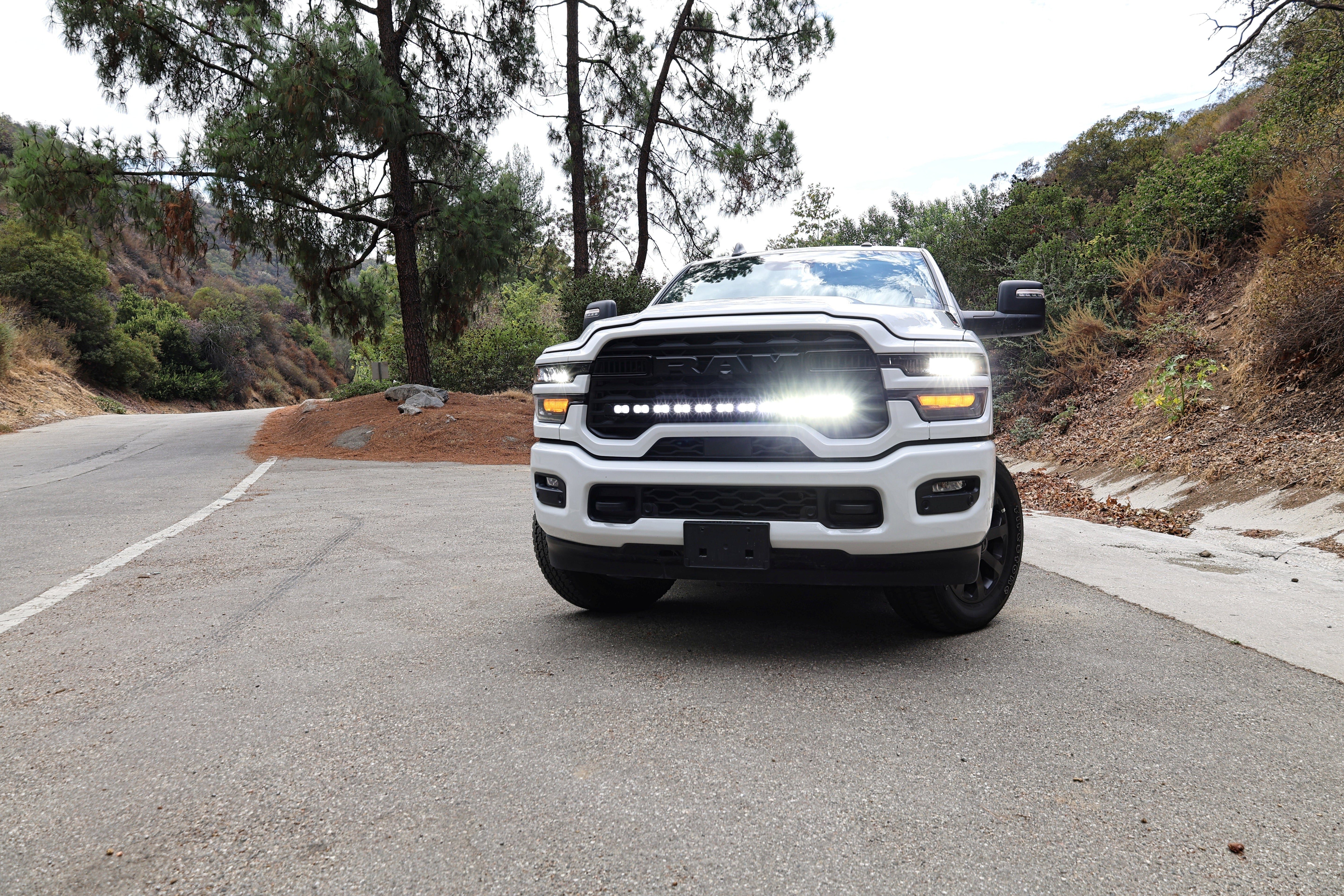 2025+ RAM 2500 light bar 40in PRO curved LED installed on white RAM 2500 truck front view on mountain road