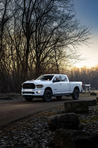 RAM 2500 Fog Light Kit installed on white RAM truck driving on forest road at dusk