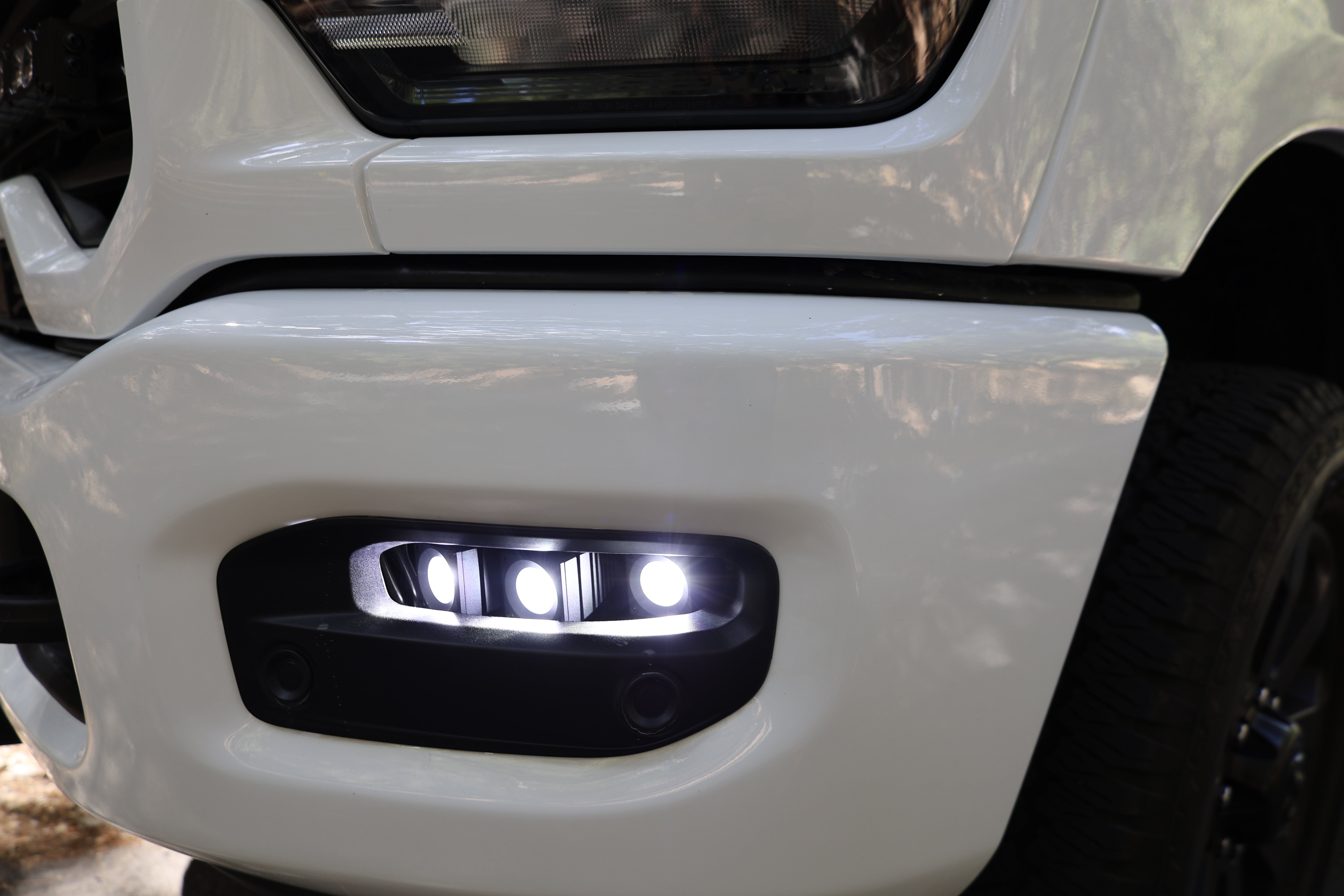 RAM 2500 Fog Light Kit installed on white RAM 2500 front bumper with bright LED fog lights illuminated