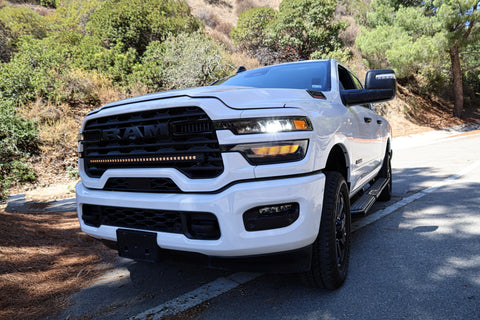2025+ RAM 2500 light bar slim 40in curved LED installed on white RAM 2500 truck front grille on mountain road