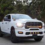White RAM 2500 truck with upgraded RAM 2500 Fog Light Kit installed and illuminated on a city street at dusk