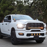White RAM 2500 truck with upgraded RAM 2500 Fog Light Kit installed and illuminated on a city street at dusk