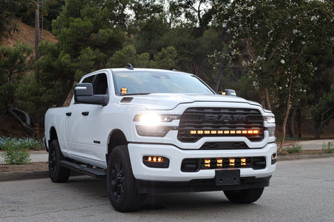 White RAM 2500 truck with upgraded RAM 2500 Fog Light Kit installed and illuminated on a city street at dusk