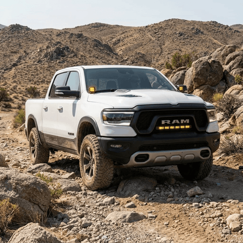 RAM REBEL light bar PRO installed on white RAM 1500 Rebel driving off-road between grille and bumper in rocky desert