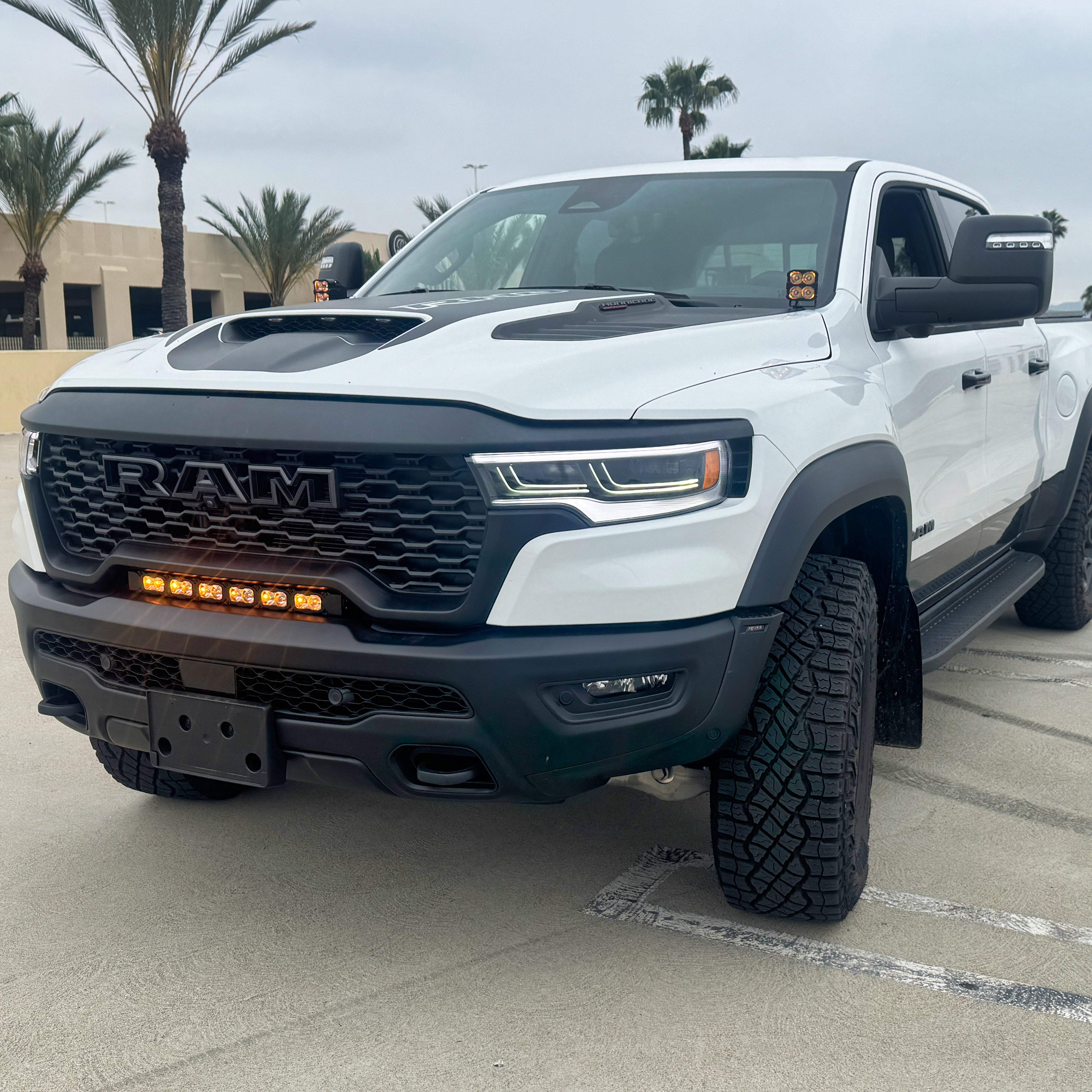 RAM RHO light bar PRO installed on white RAM 1500 RHO between grille and bumper, slim curved LED front lighting upgrade