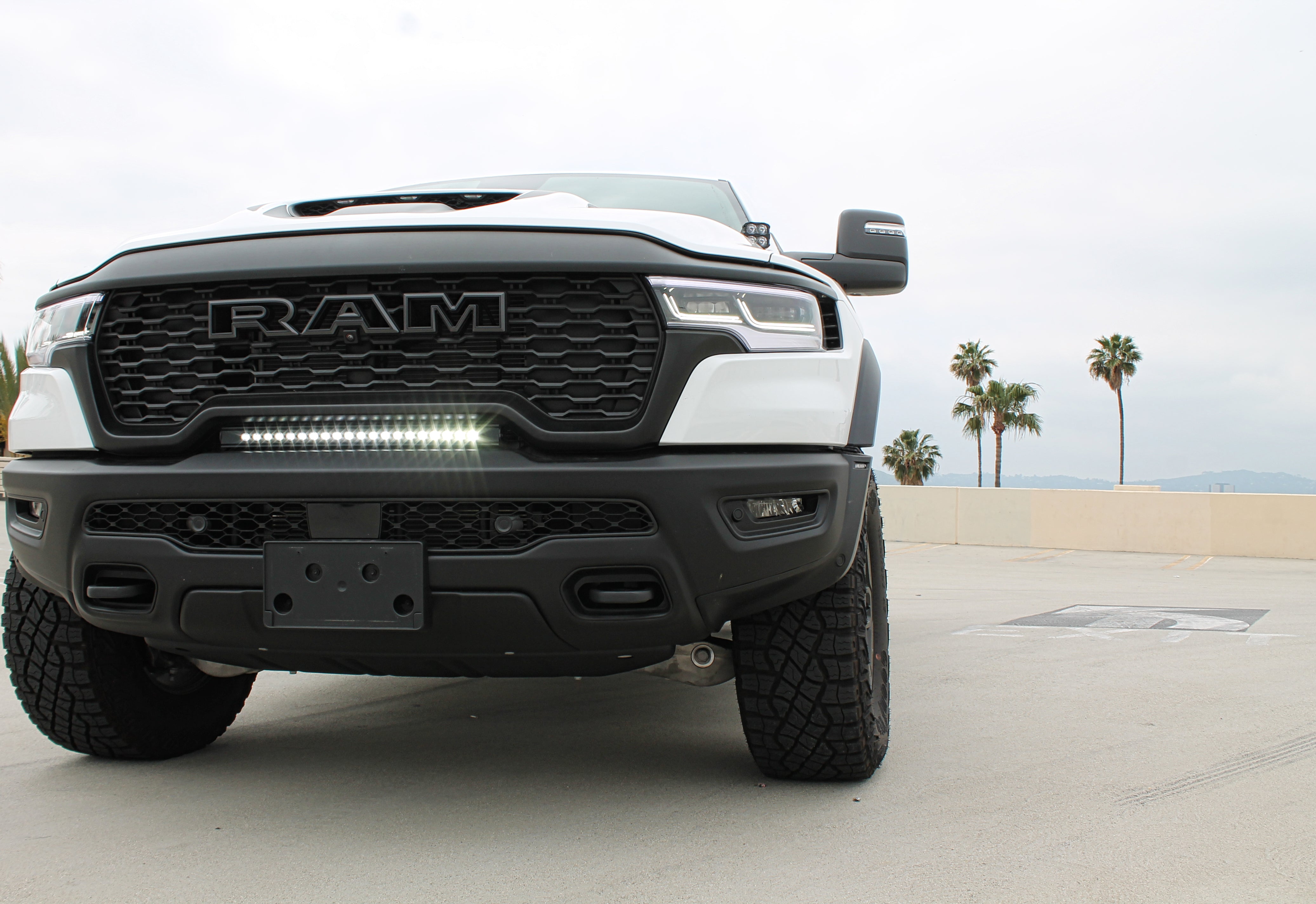 RAM RHO lightbar on 2025+ RAM 1500 Rebel between grille and bumper; slim curved light bar with black powder-coated bracket, 23in length