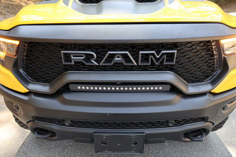 RAM TRX Light bar slim 23in curved LED mounted in factory grille opening on yellow 2021-2024 RAM 1500 TRX front bumper