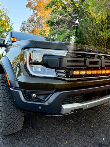 2024 Ford Ranger Raptor with hood mount LED lights showcasing amber DRL backglow in outdoor setting.