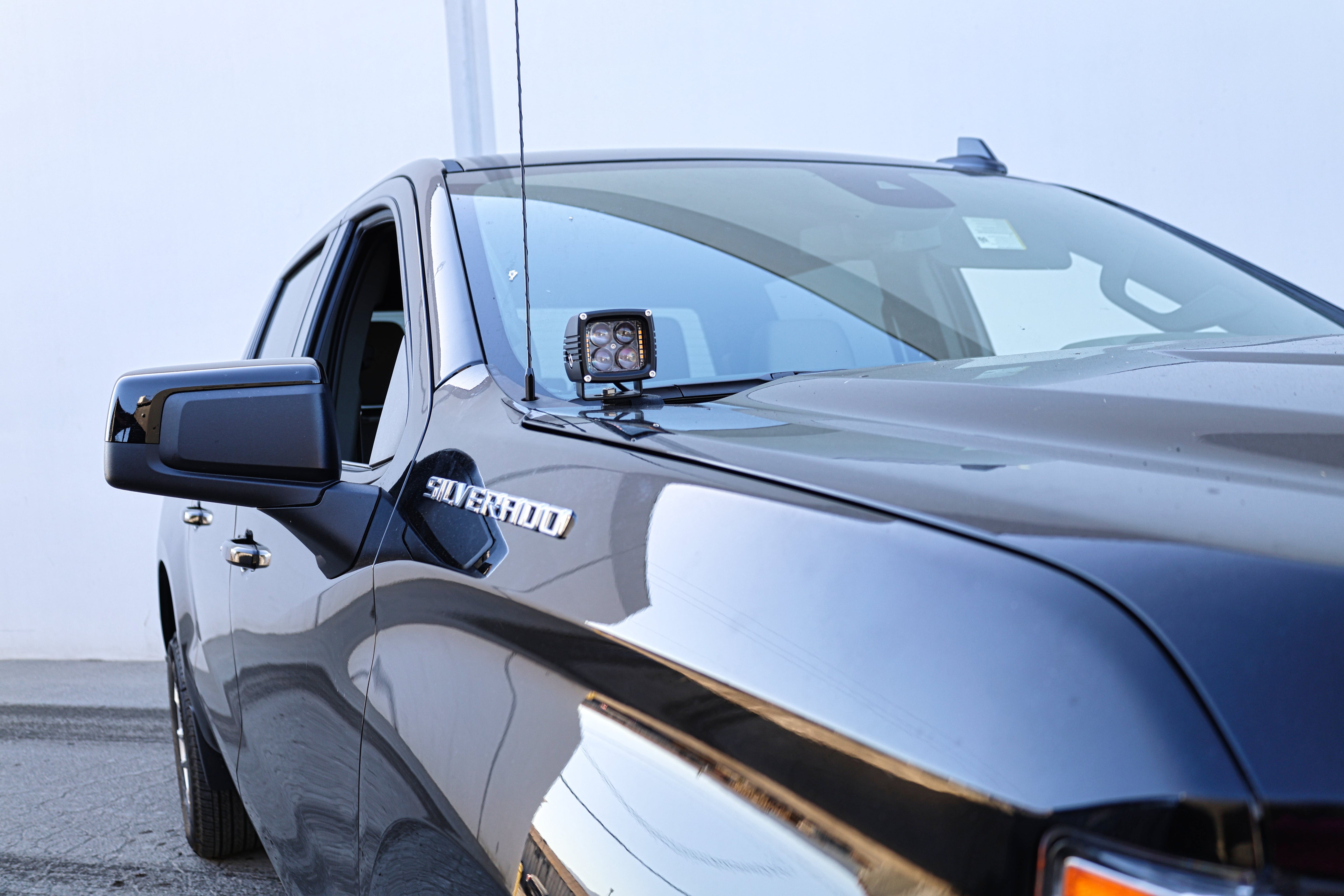 Silverado 1500 ditch lights mounted on driver side hood of black 2022 Chevrolet Silverado truck