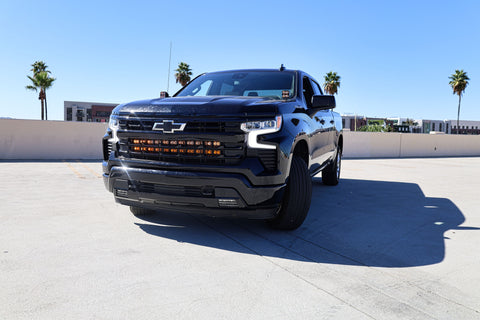 Black Chevrolet Silverado 1500 ditch lights PRO dual color LED upgrade on front bumper in sunny parking lot