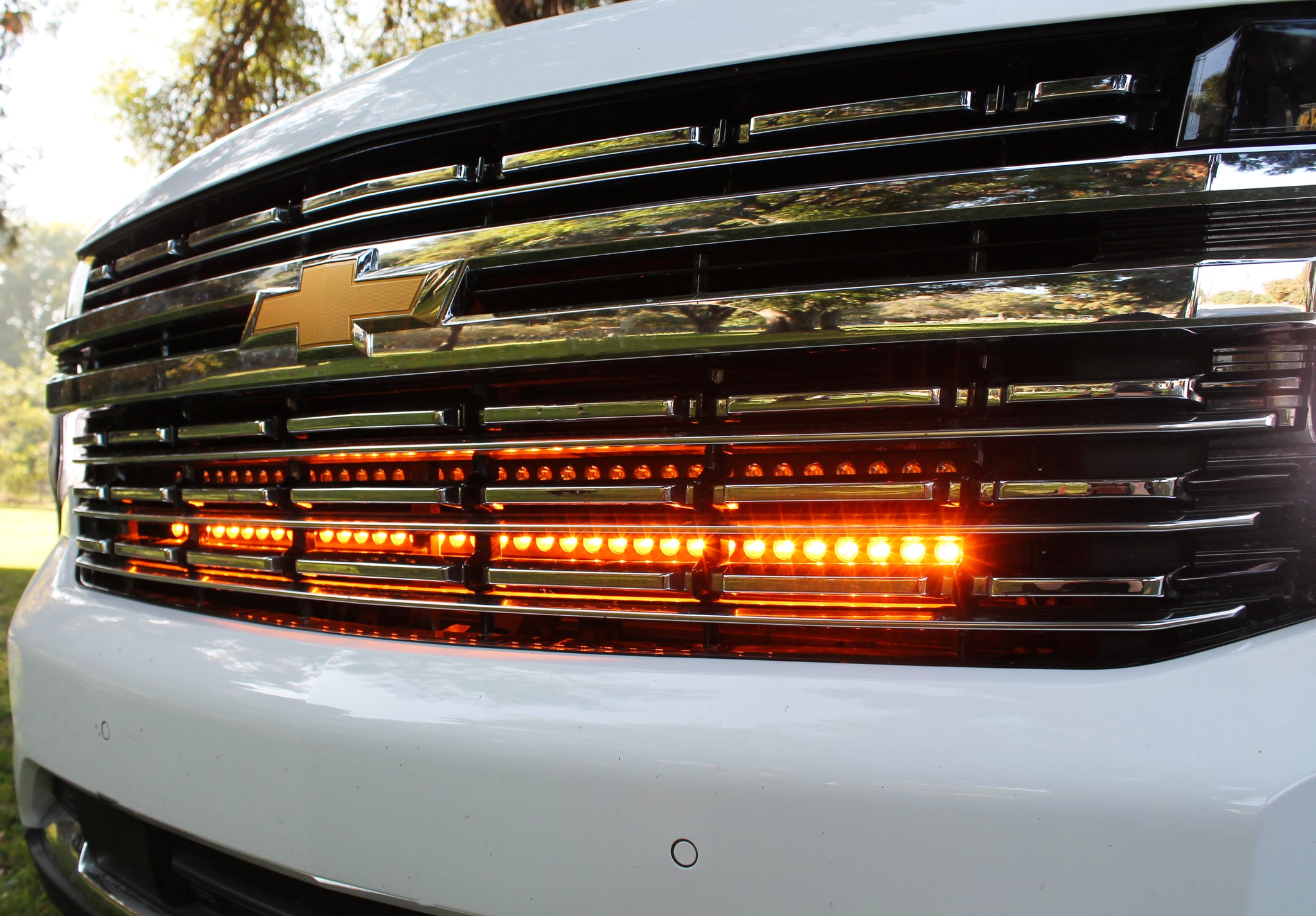 white 2021 2022 2023 2024 Chevrolet Suburban with one led amber light bars behind the grille for off roading