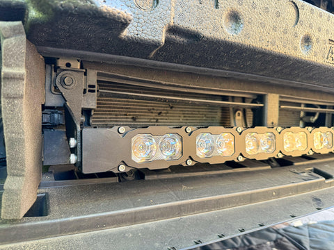 grey subaru outback with installed  led light bar behind the grille off roading