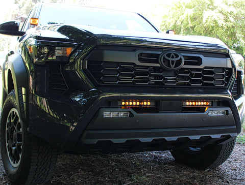 black 2024 toyota tacoma with amber led light bars behind the grille and amber ditch lights