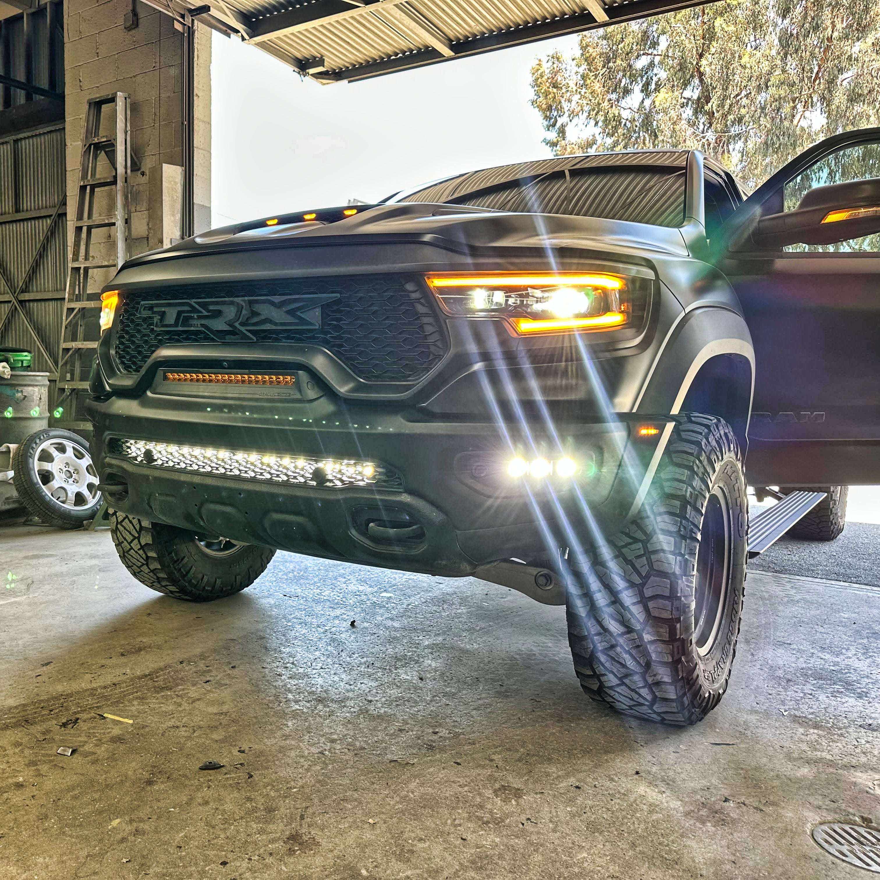 Black 2019-2024 RAM 1500 TRX with fog light kit white LEDs lit in the front bumper, front corner view