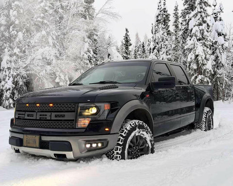 red ford raptor generation 1 2010 2011 2012 2013 2014 in the snow with off roading fog light kit 