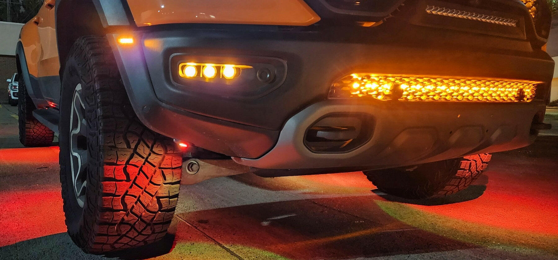 RAM Rebel fog light kit 2019-2024 with amber LED fog lights and light bar illuminated on front bumper at night