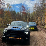 RAM Rebel Light Bar on 2019-2024 RAM 1500 Rebel trucks driving through a wooded dirt trail with LED lights on