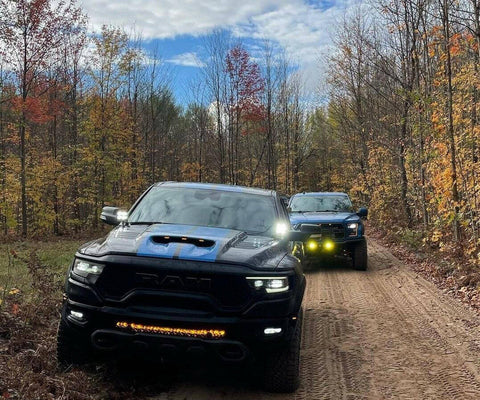 RAM Rebel Light Bar on 2019-2024 RAM 1500 Rebel trucks driving through a wooded dirt trail with LED lights on