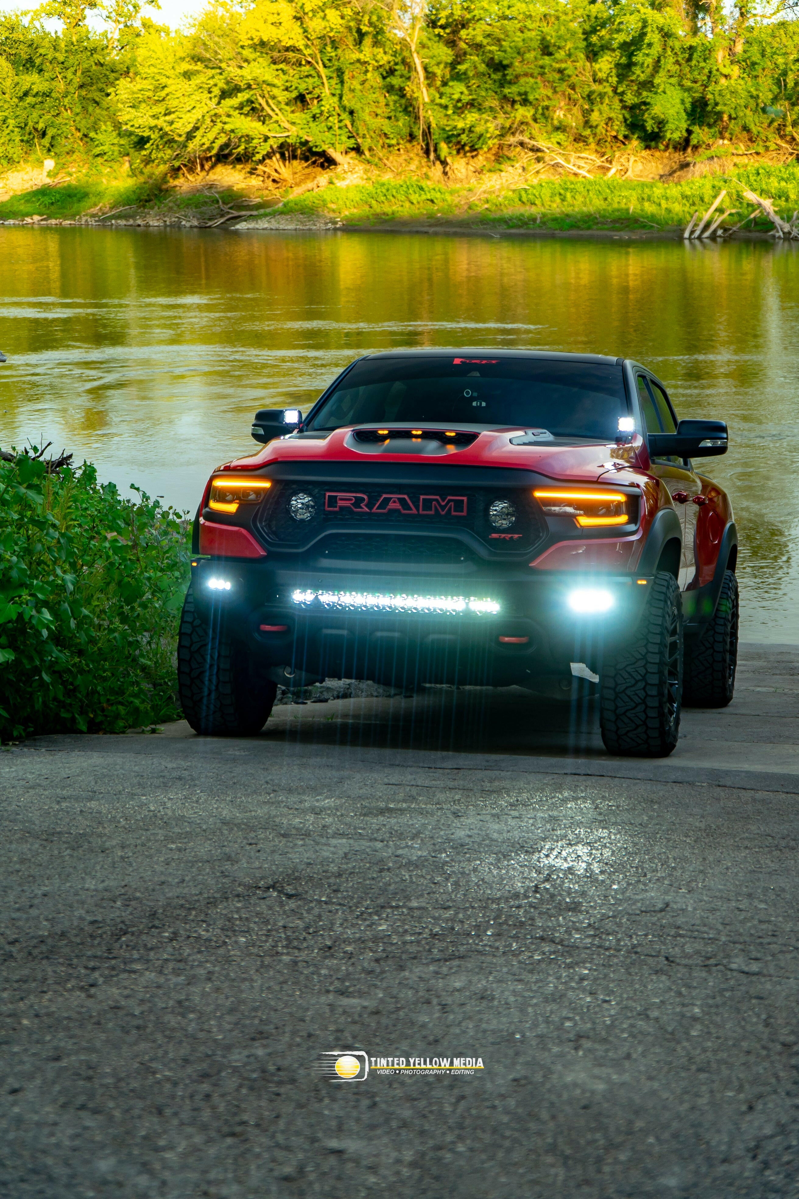 Red RAM 1500 with RAM Rebel Light Bar single 40in slim light bar illuminated at river boat ramp front view