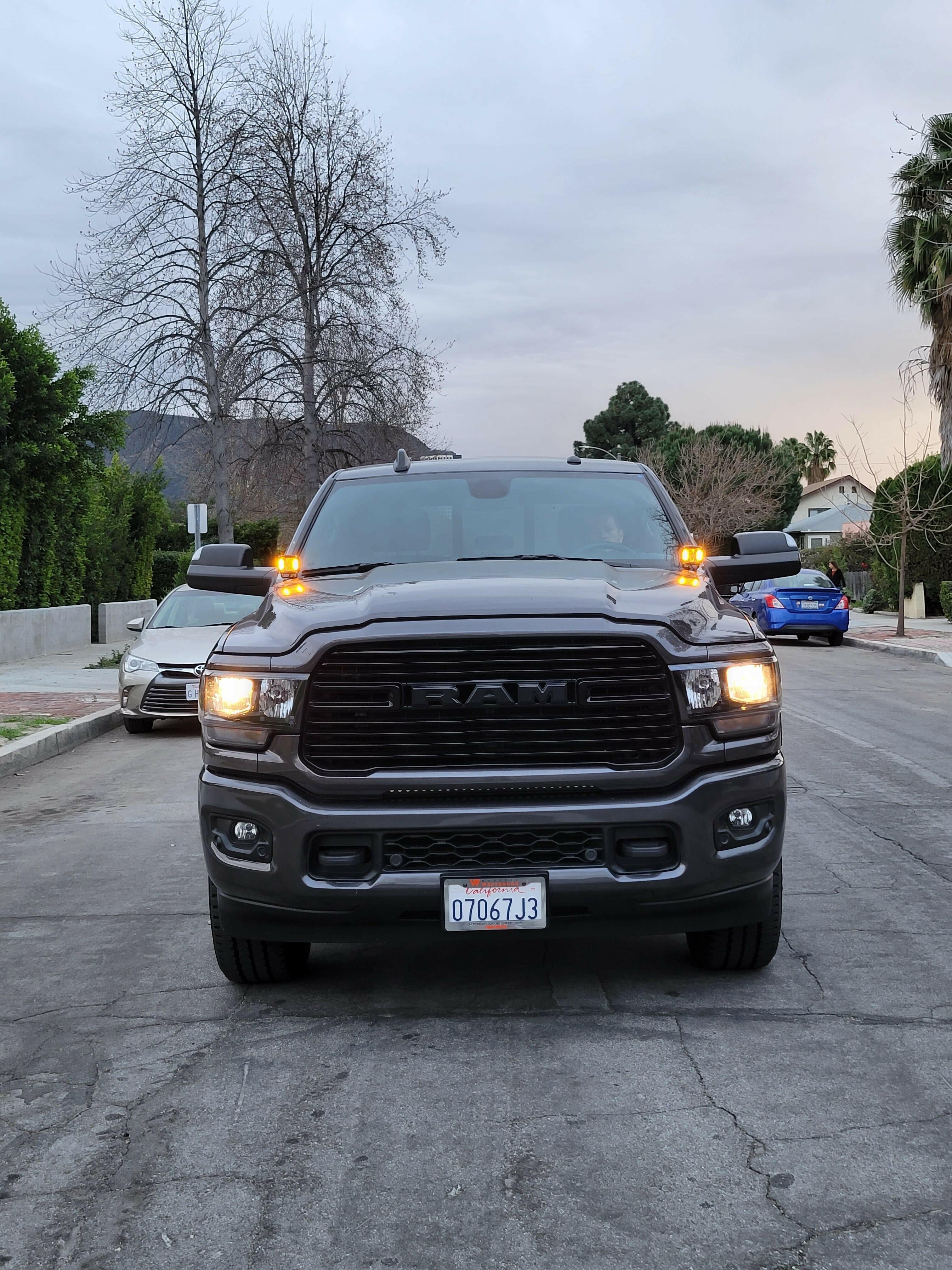 2025+ RAM 2500 3500 Ditch Lights with dual color amber DRL glowing on front of black RAM HD truck on residential street